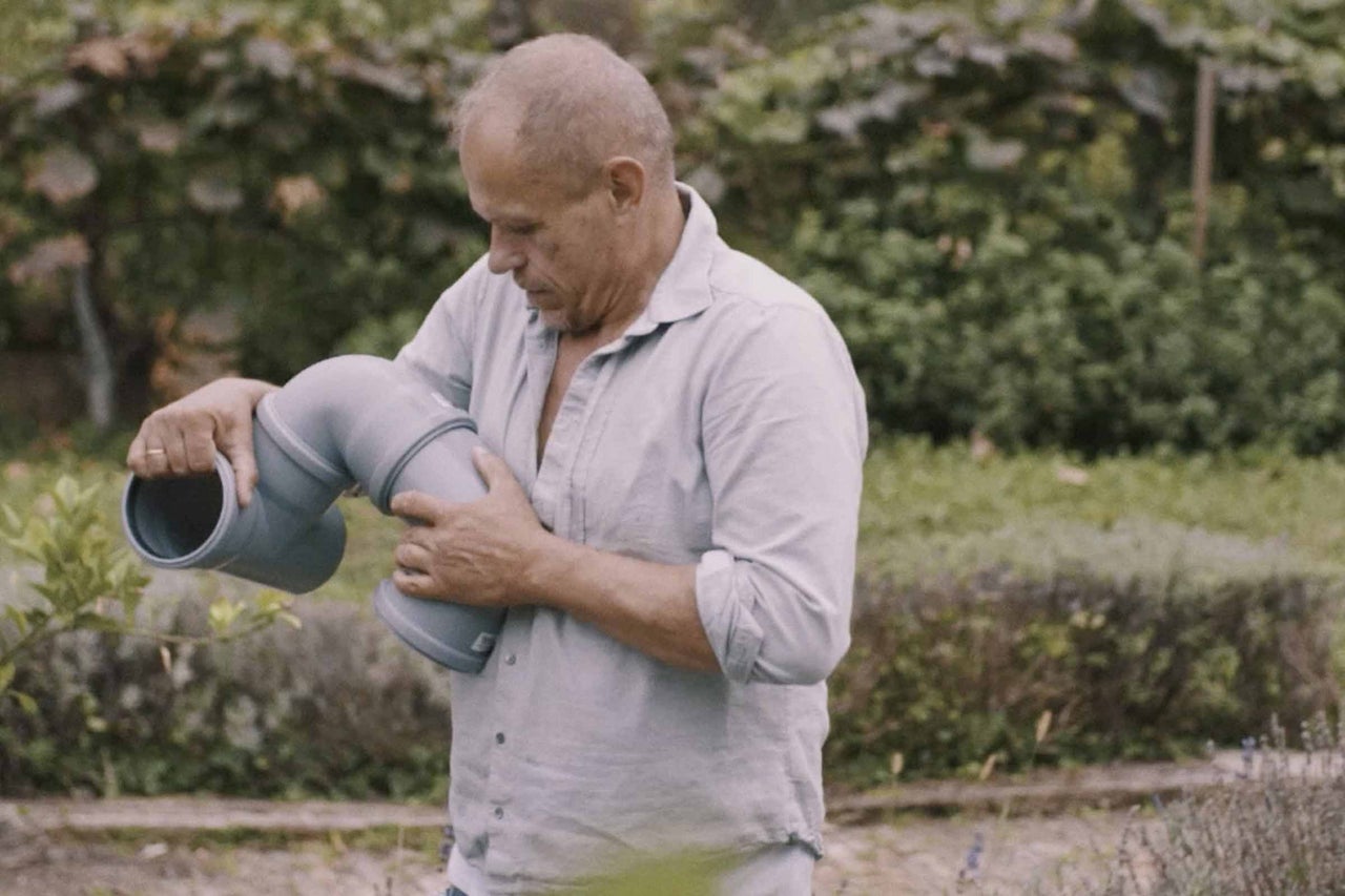 Muž drží v ruke odpadovú rúru vhodnú na sanitárne inštalácie.