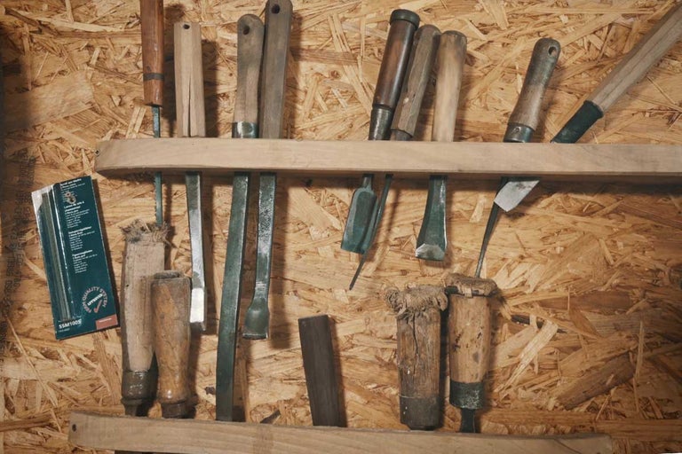 Nástroje, ako sú dláta a pilníky, na drevenej polici pred drevotrieskovou doskou