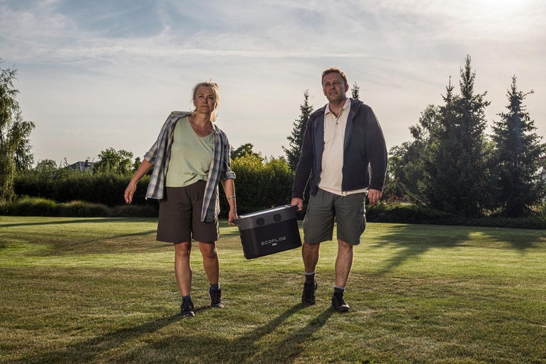 Dvaja ľudia nesú prenosnú elektráreň Ecoflow na trávniku.