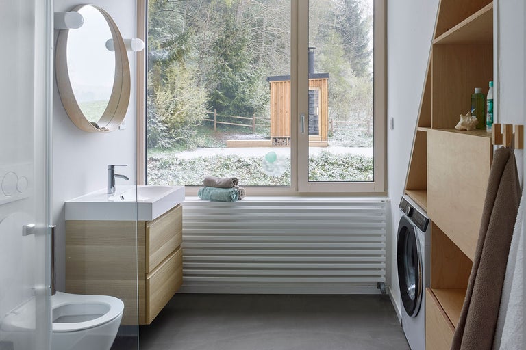 Moderná kúpeľňa s umývadlom, zrkadlom, radiátorom, práčkou a výhľadom von