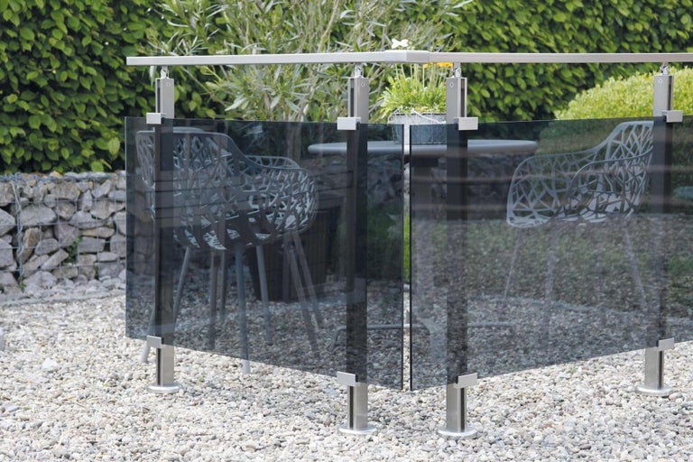 Záhradná scéna so skleneným plotom a nerezovými stĺpikmi na štrkovom povrchu