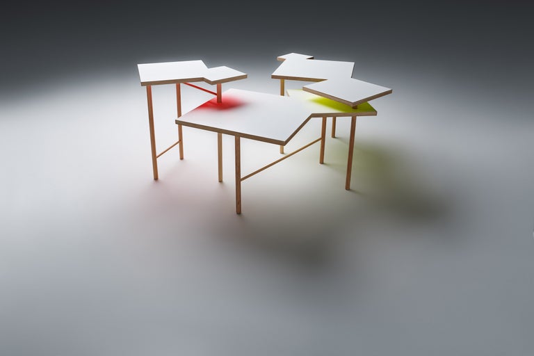 Niekoľko spojených odkladacích stolíkov z dreva a lakovanej dosky.