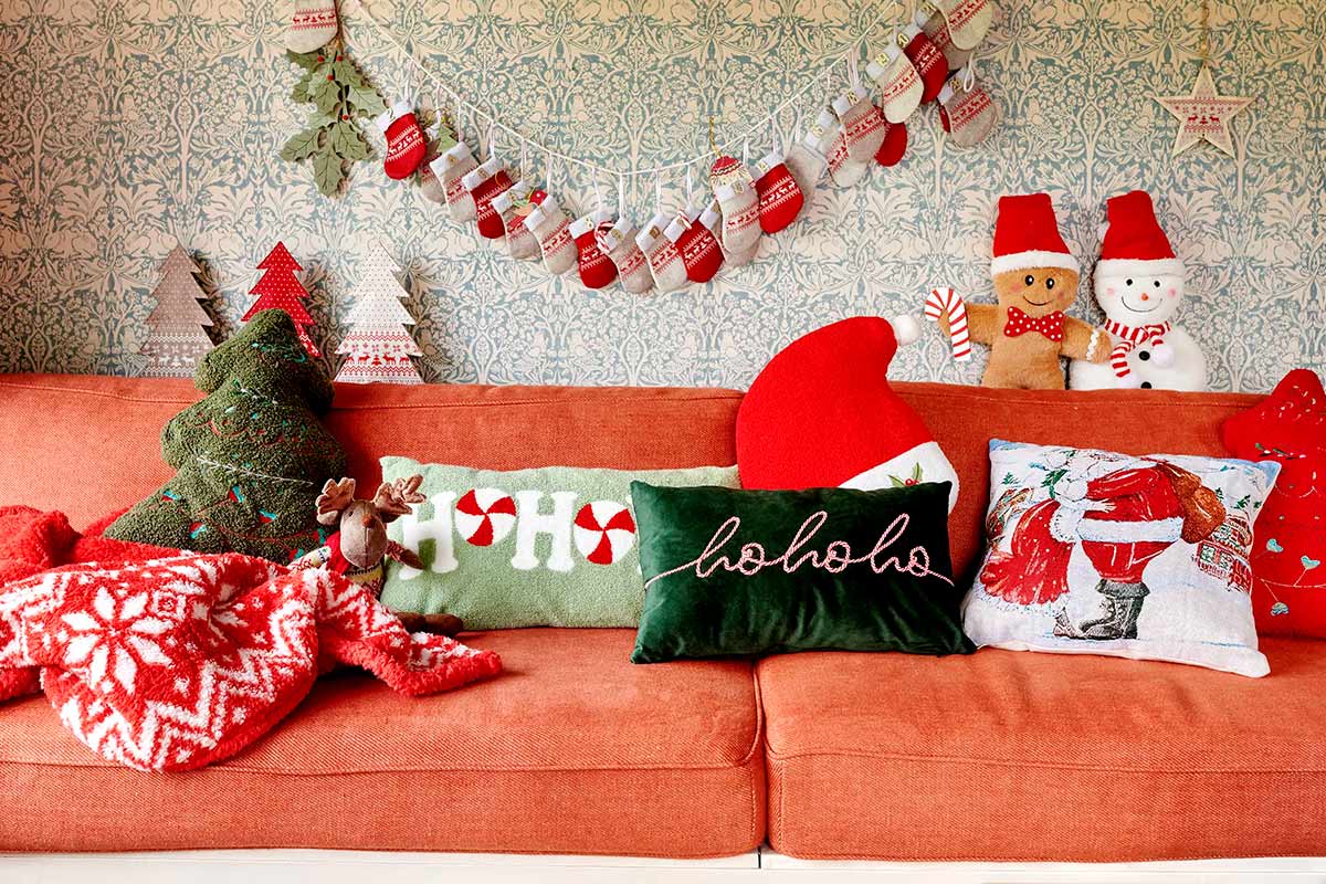 Ozdobná obývacia izba s vianočnými motívmi na oranžovej pohovke.