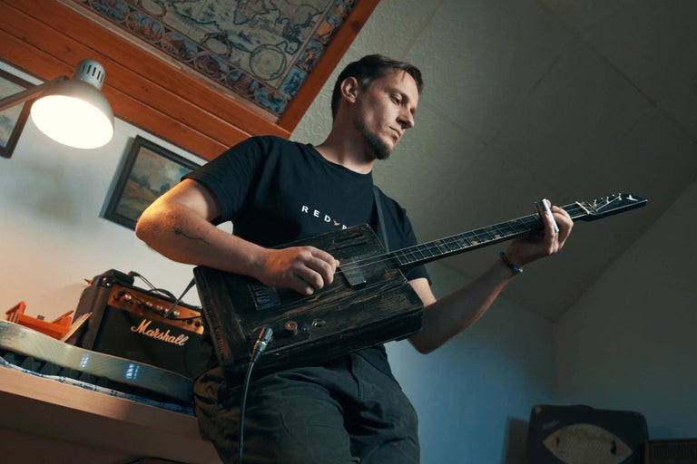 Muž hrá na gitaru z cigár vedľa zosilňovača Marshall