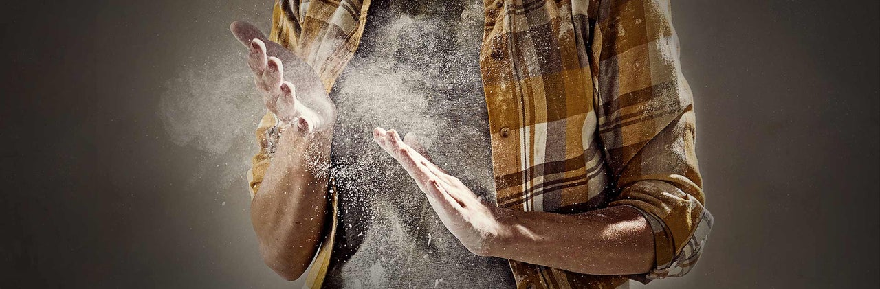 Muž s prachom na rukách a kockovanou košeľou