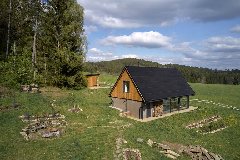 Krajinný pohľad na drevený dom s čiernou strechou a vedľajšou budovou