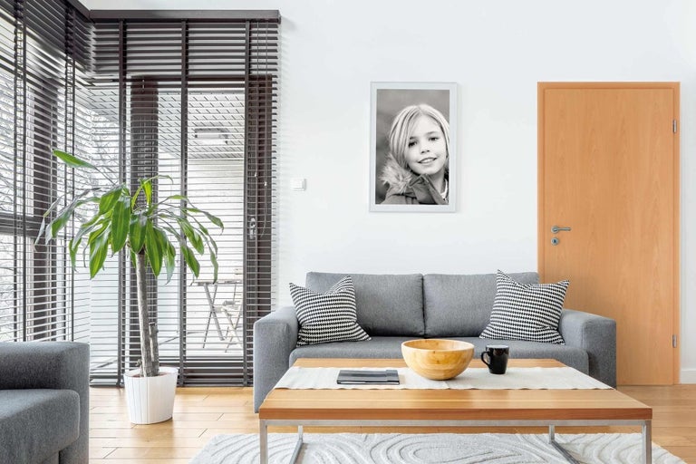 Obývacia izba s pohovkou, konferenčným stolíkom, izbovou rastlinou a zarámovaným portrétom