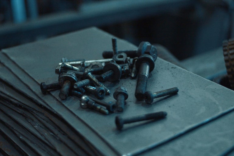 Zbierka rôznych skrutiek a matíc na kovovom povrchu.