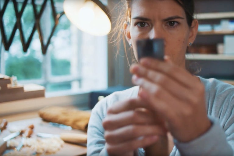 Žena kontroluje dláto na pozadí dielne