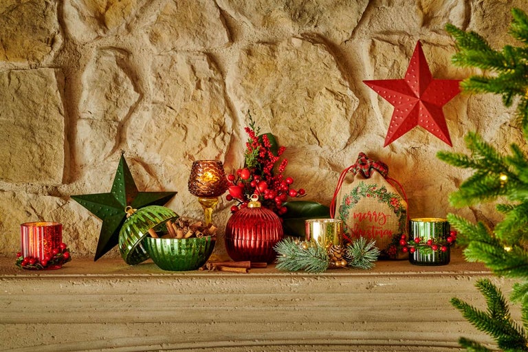 Ozdobný krb s vianočnými dekoráciami, vrátane svietnikov, hviezd a darčekovej tašky