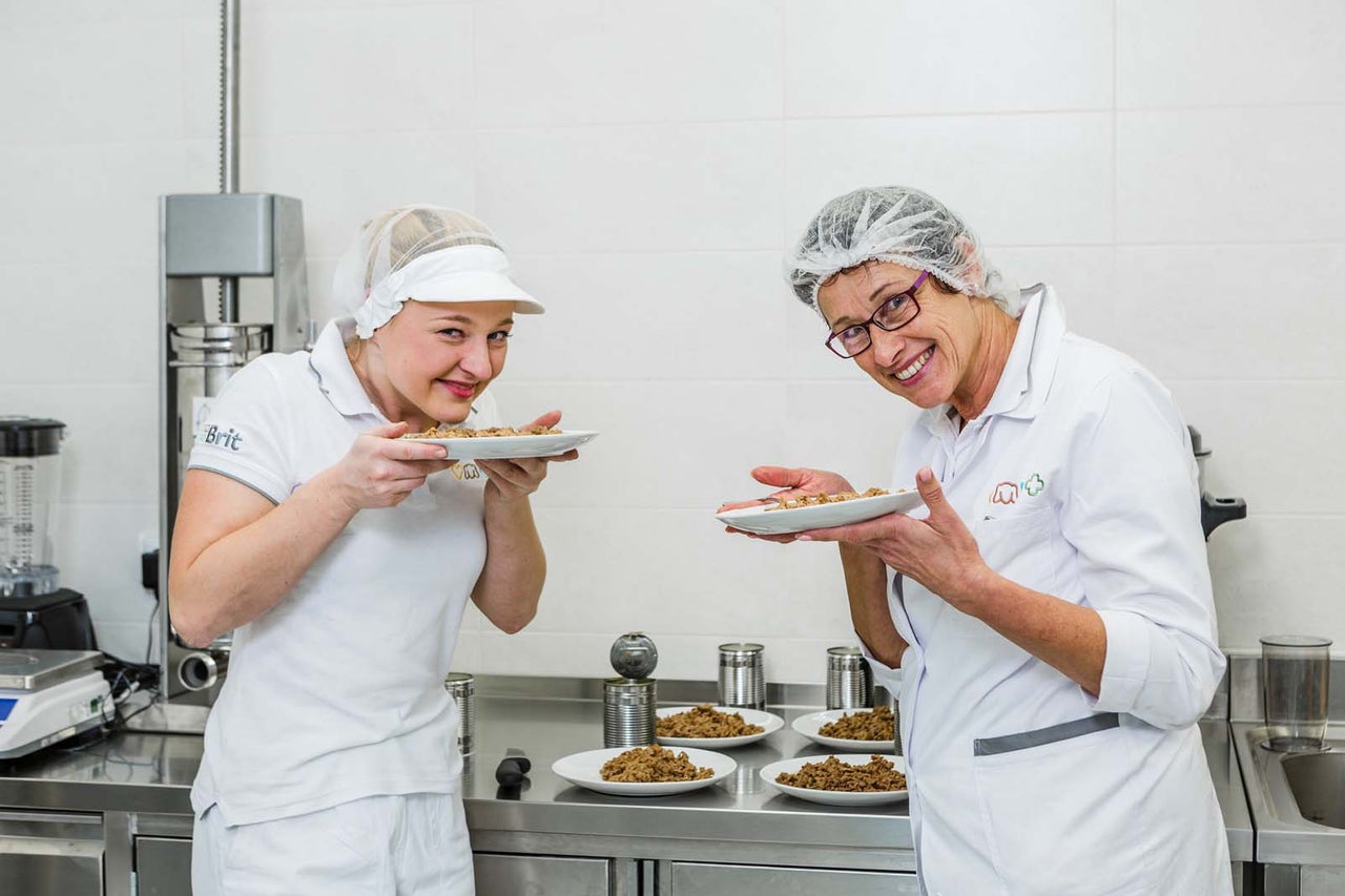 Dvaja ľudia v laboratórnom oblečení držia taniere s krmivom pre zvieratá v laboratóriu