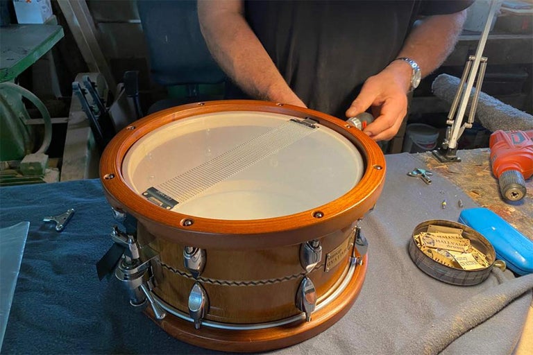 Remeselník montuje drevený bubon pomocou nástrojov na pracovnom stole