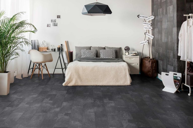 Spálňa s tmavou vinylovou podlahou v dizajne dreva, posteľou, písacím stolom a dekoráciami