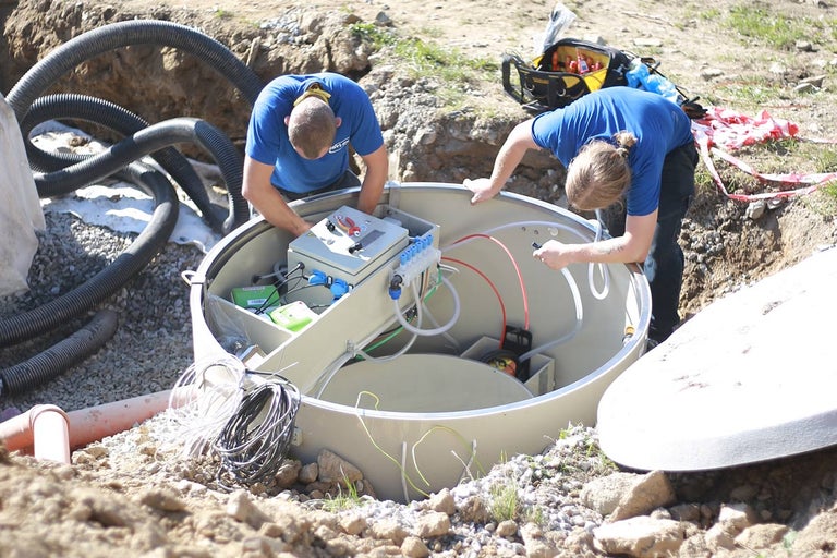 Dvaja pracovníci inštalujú vonkajšiu čističku odpadových vôd.