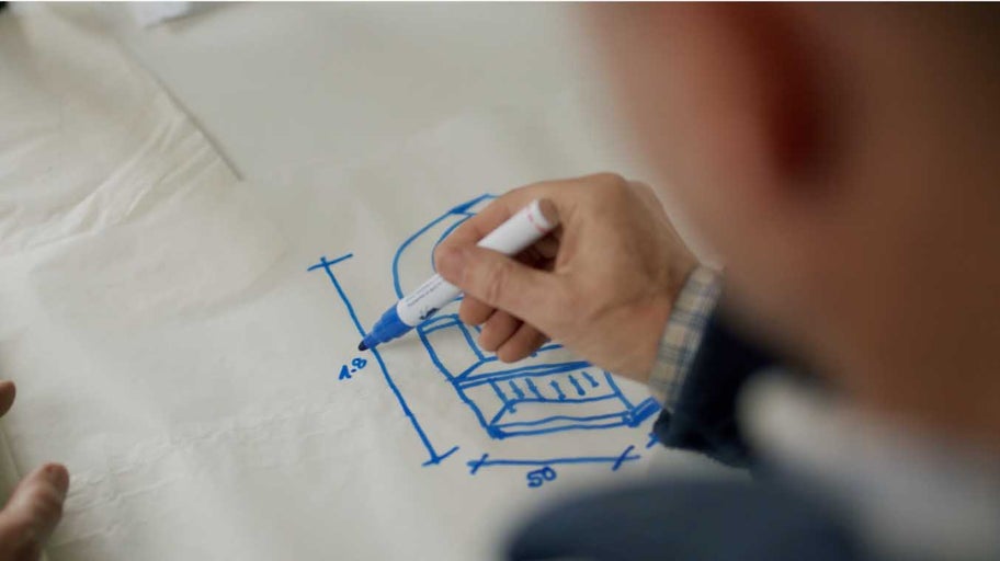Osoba kreslí skicu nábytku fixkou na papier.