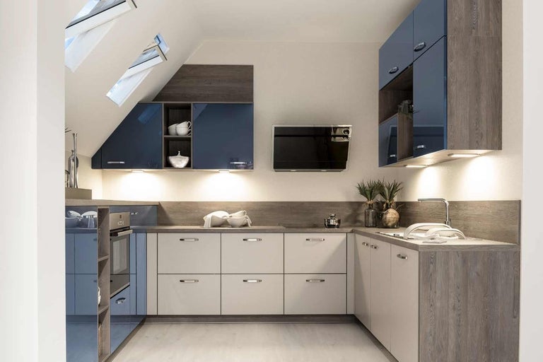 Kuchyňa s hornými a dolnými skrinkami a vstavanými spotrebičmi pod strešnými oknami