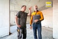 Dvaja remeselníci diskutujú o stavebnom projekte v hrubej miestnosti