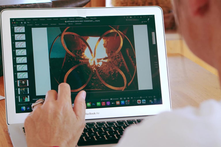 Osoba pracuje na MacBooku Air s prezentáciou o kvetinovej ceste.