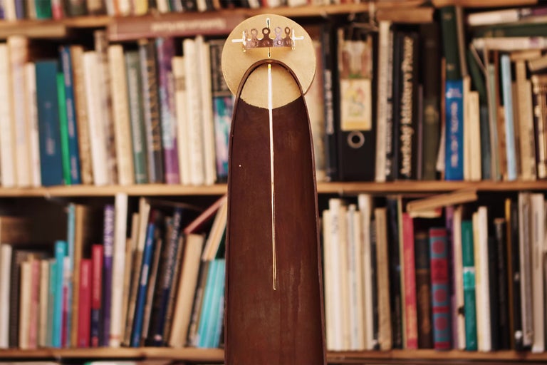 Dekoratívny predmet s kruhovou hlavou a podlhovastým telom pred knižnicou