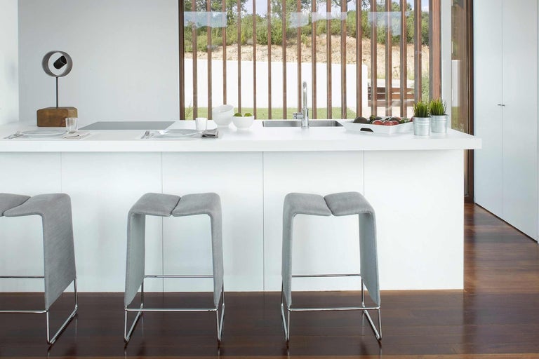 Moderná kuchyňa s dvoma barovými stoličkami a bielym kuchynským ostrovom.