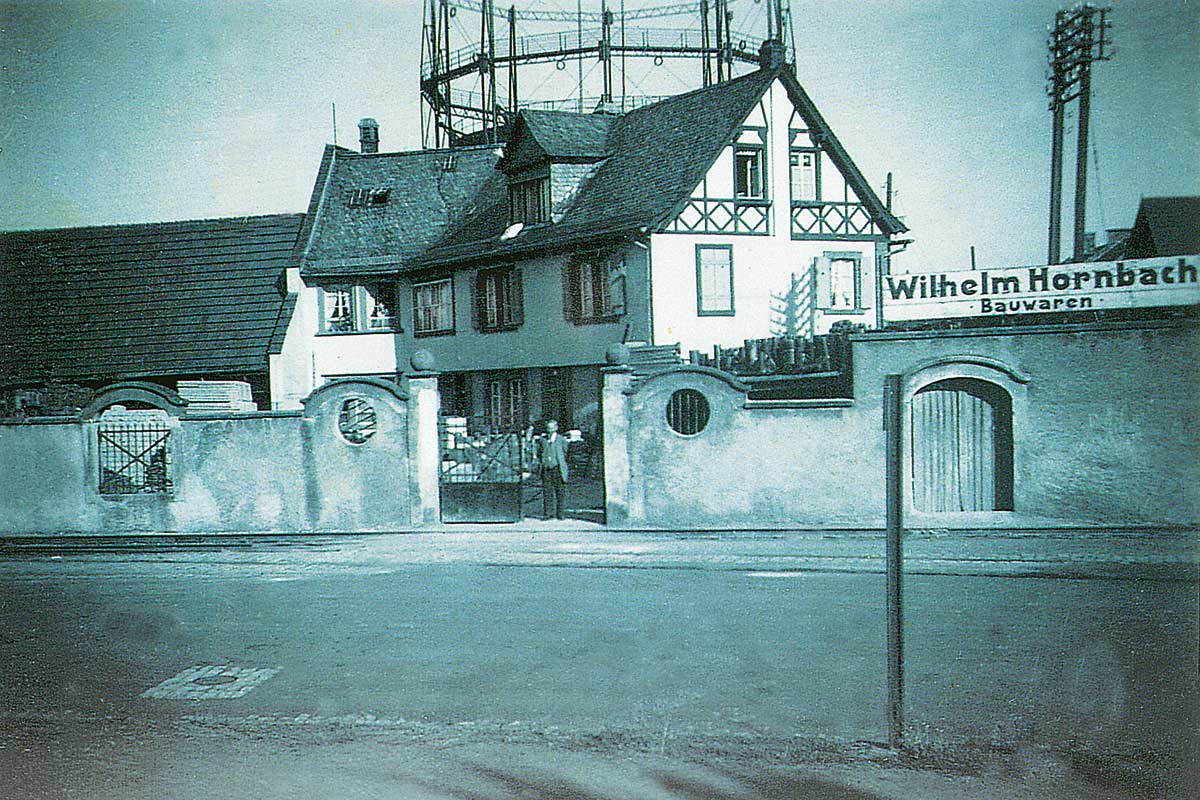 Historická fotografia obchodu so stavebninami Wilhelm Hornbach s budovami a plynojemom
