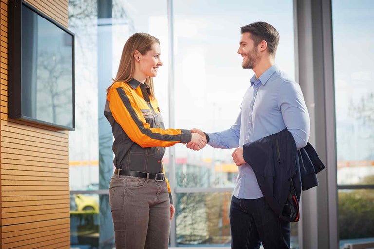 Zamestnankyňa spoločnosti Hornbach si potriasa rukou so zákazníkom na privítanie.