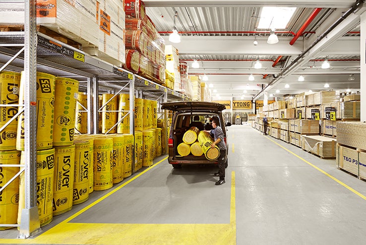 Regály s rolkami izolácie v predajni Hornbach, zákazník nakladá dodávku.