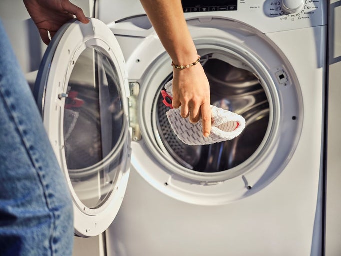 Osoba vkladá návlek na mop do práčky.