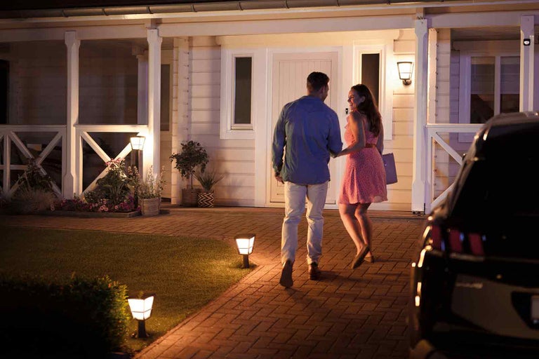 Osvetlený dom so záhradným chodníkom a párom