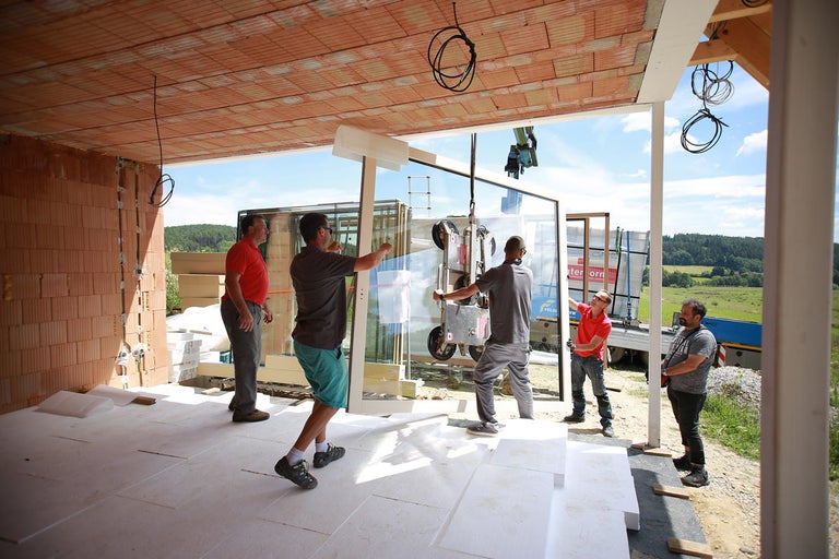 Montáž veľkého okenného prvku žeriavom na stavenisku.