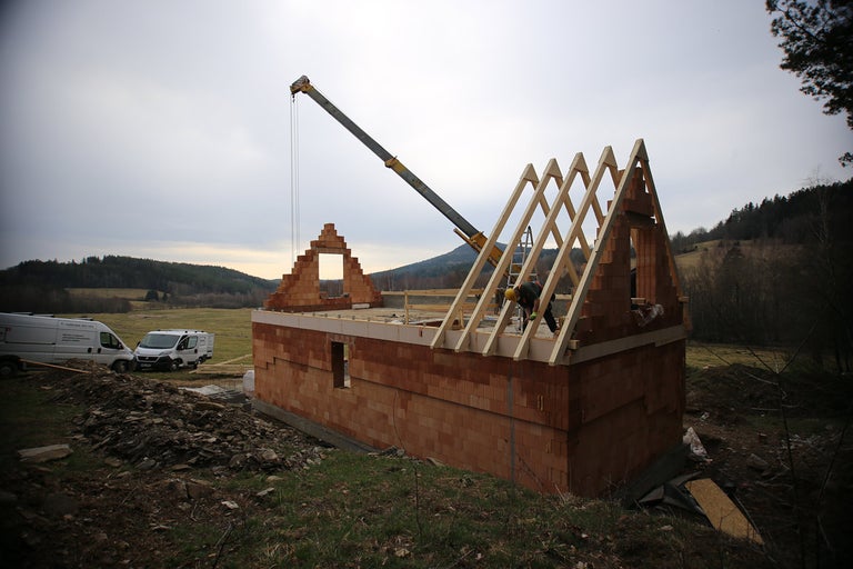 Stavenisko domu s tehlovou stenou a drevenou konštrukciou strechy