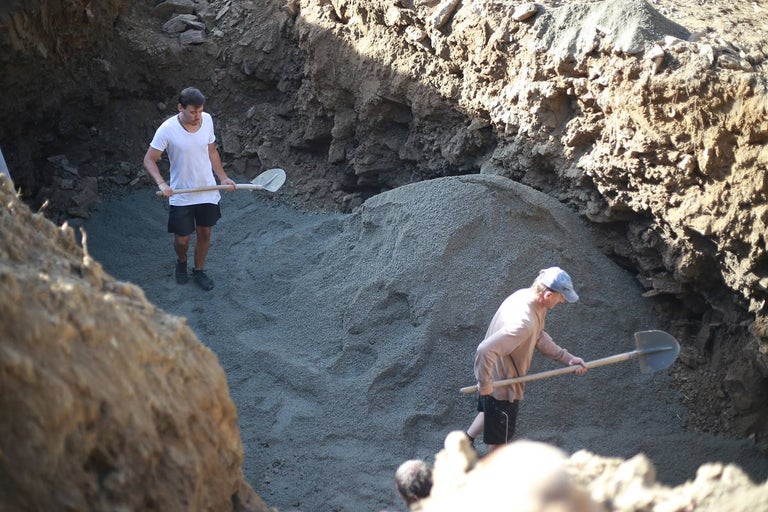 Dve osoby pracujú s lopatami vo výkope.