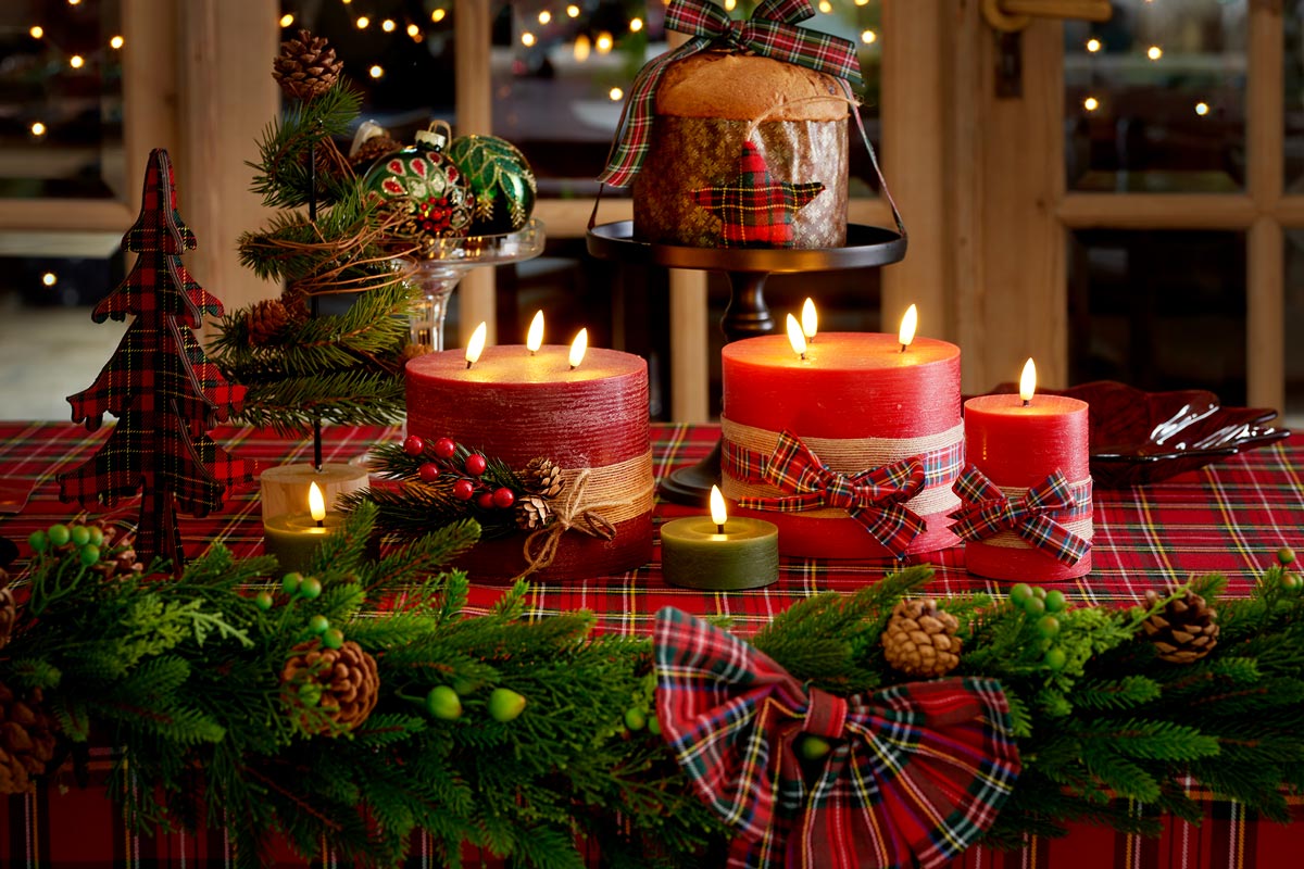 Slávnostne prestretý stôl s horiacimi sviečkami, jedľovou zeleňou, dekoráciami a panettone