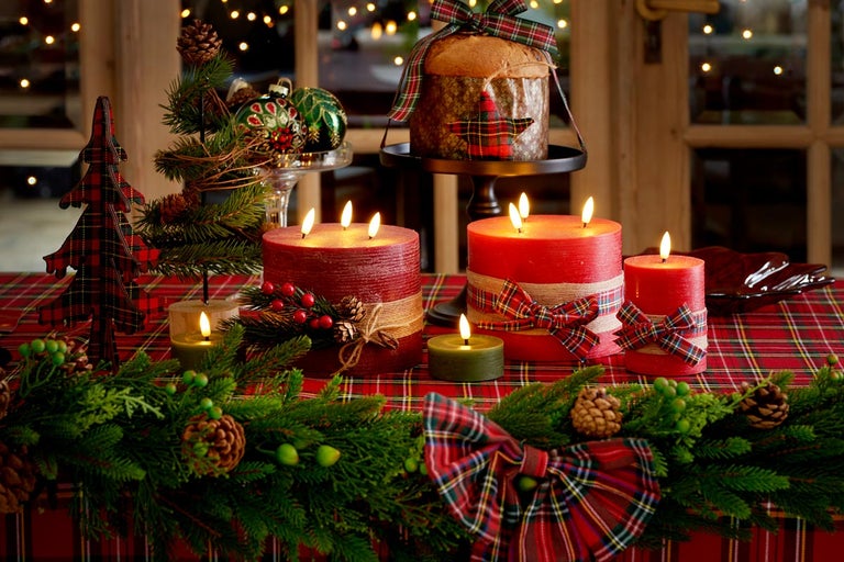 Slávnostne prestretý stôl s horiacimi sviečkami, jedľovou zeleňou, dekoráciami a panettone