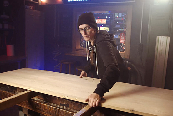 Žena pracuje s drevenou doskou na pracovnom stole.