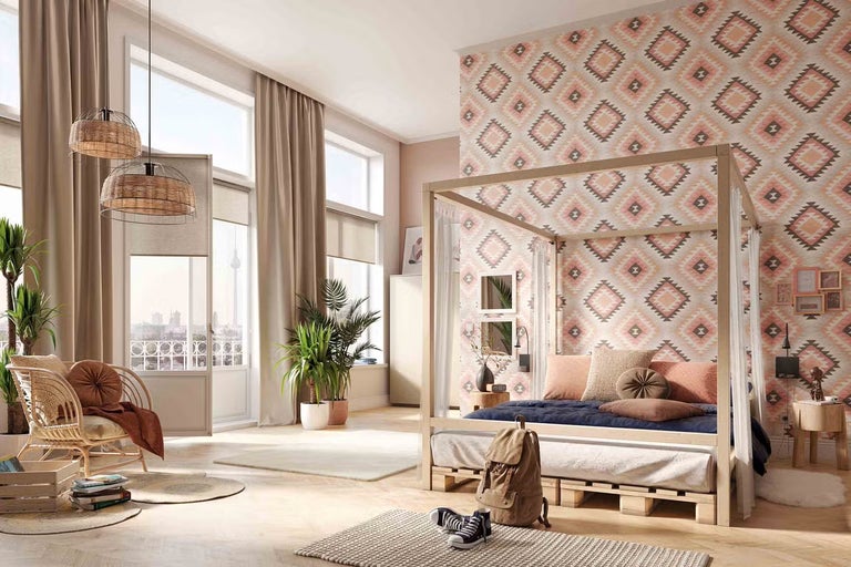 Svetlá spálňa s posteľou s nebesami z paletového dreva, geometrickou tapetou, ratanovým kreslom, pletenými lampami a veľkými oknami.