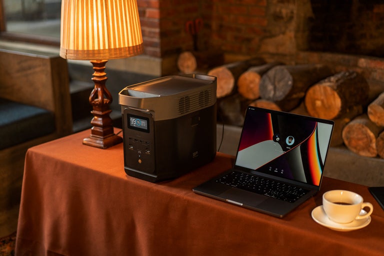 Prenosná napájacia stanica vedľa notebooku a šálky kávy na stole