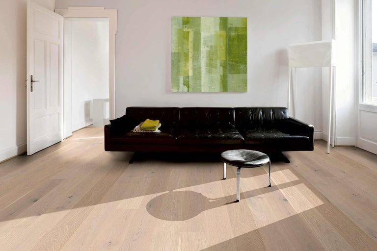 Svetlá drevená podlaha v obývacej izbe s pohovkou a umeleckým dielom