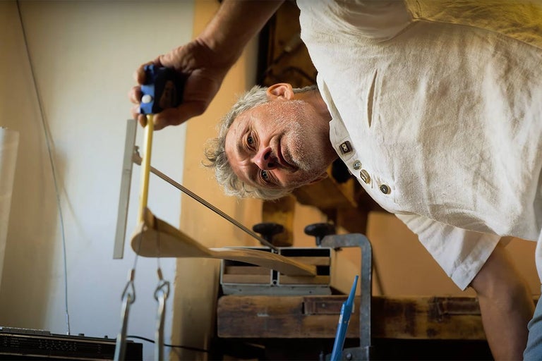 Muž pracuje s drevoobrábacím strojom a meracími nástrojmi.