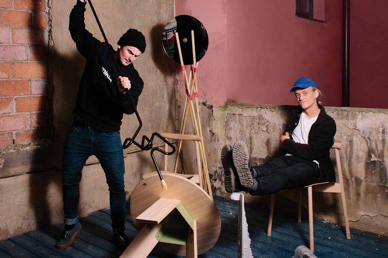 Scéna s dvoma ľuďmi, lampou a nábytkom v miestnosti s neomietnutými stenami