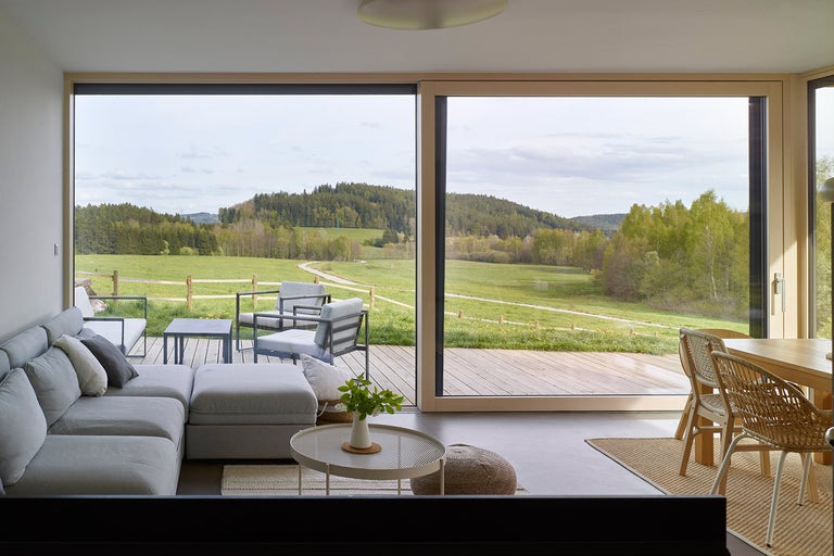 Svetlá obývacia izba s veľkými oknami a výhľadom do prírody
