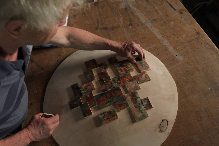 Remeselník aranžuje drevené kusy na drevenej doske pre mozaiku