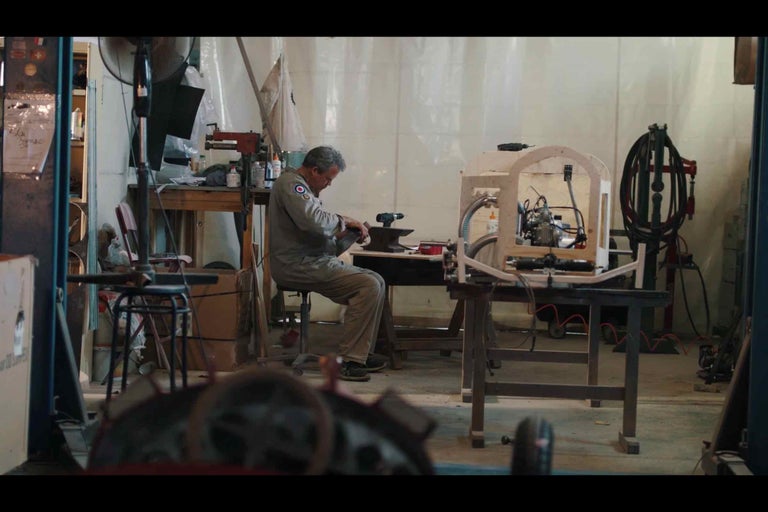 Dielňa s mužom pracujúcim na projekte, náradie a pracovný stôl