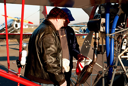 Dvaja muži kontrolujú motor lietadla na letisku.