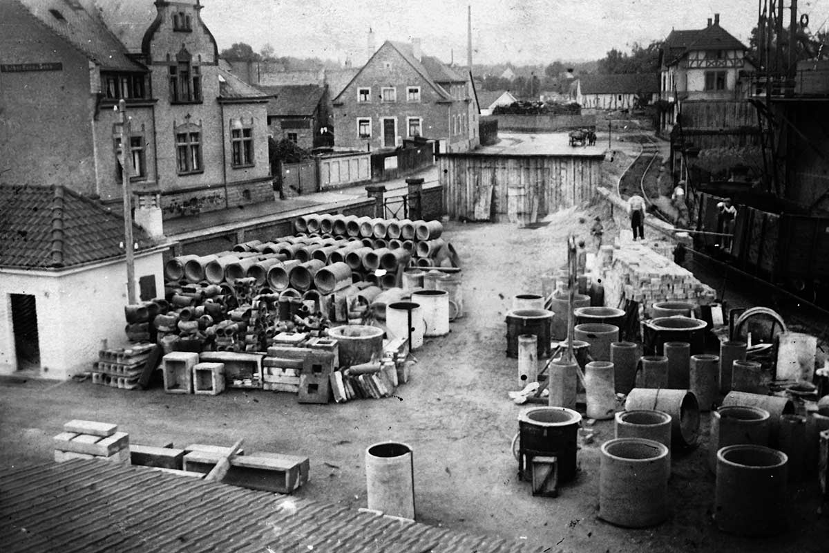 Historická fotografia skladovaných rúr a stavebných prvkov na stavenisku