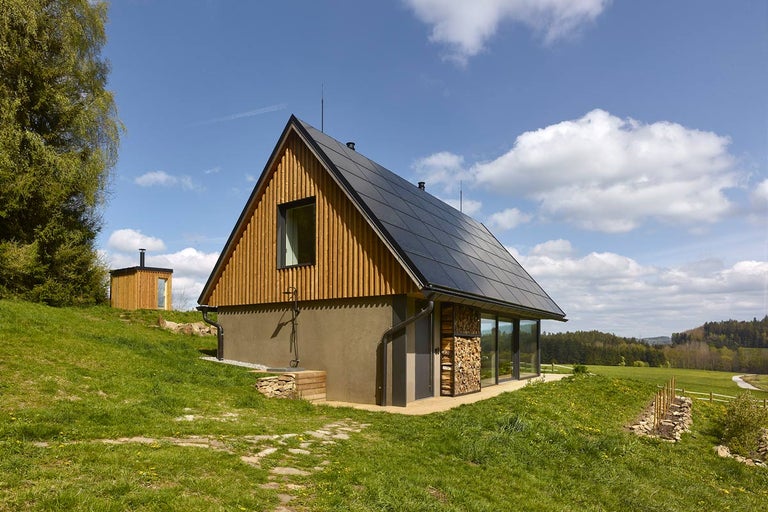 Moderný dom s dreveným obkladom, solárnym systémom a veľkými oknami vo vidieckom prostredí