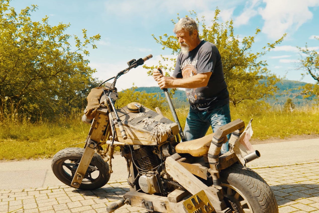 Muž stojí vedľa motocykla z dreva