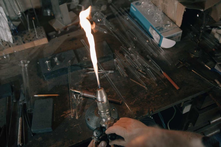 Scéna sklárne s nástrojmi a sklenenými tyčami na stole