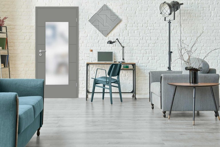 Moderná obývacia izba so sivými interiérovými dverami, písacím stolom a posedením pred bielou tehlovou stenou