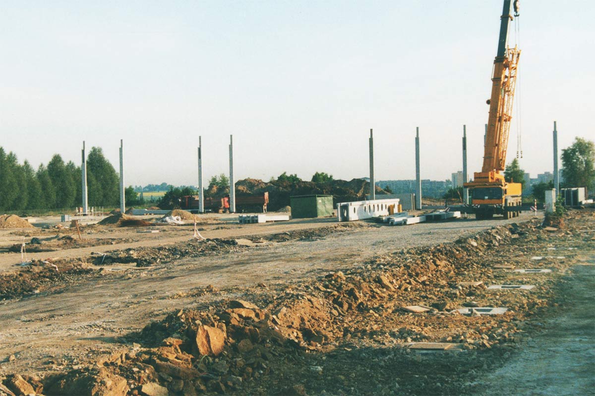 Stavenisko so žeriavom, betónovými piliermi a stavebnými materiálmi